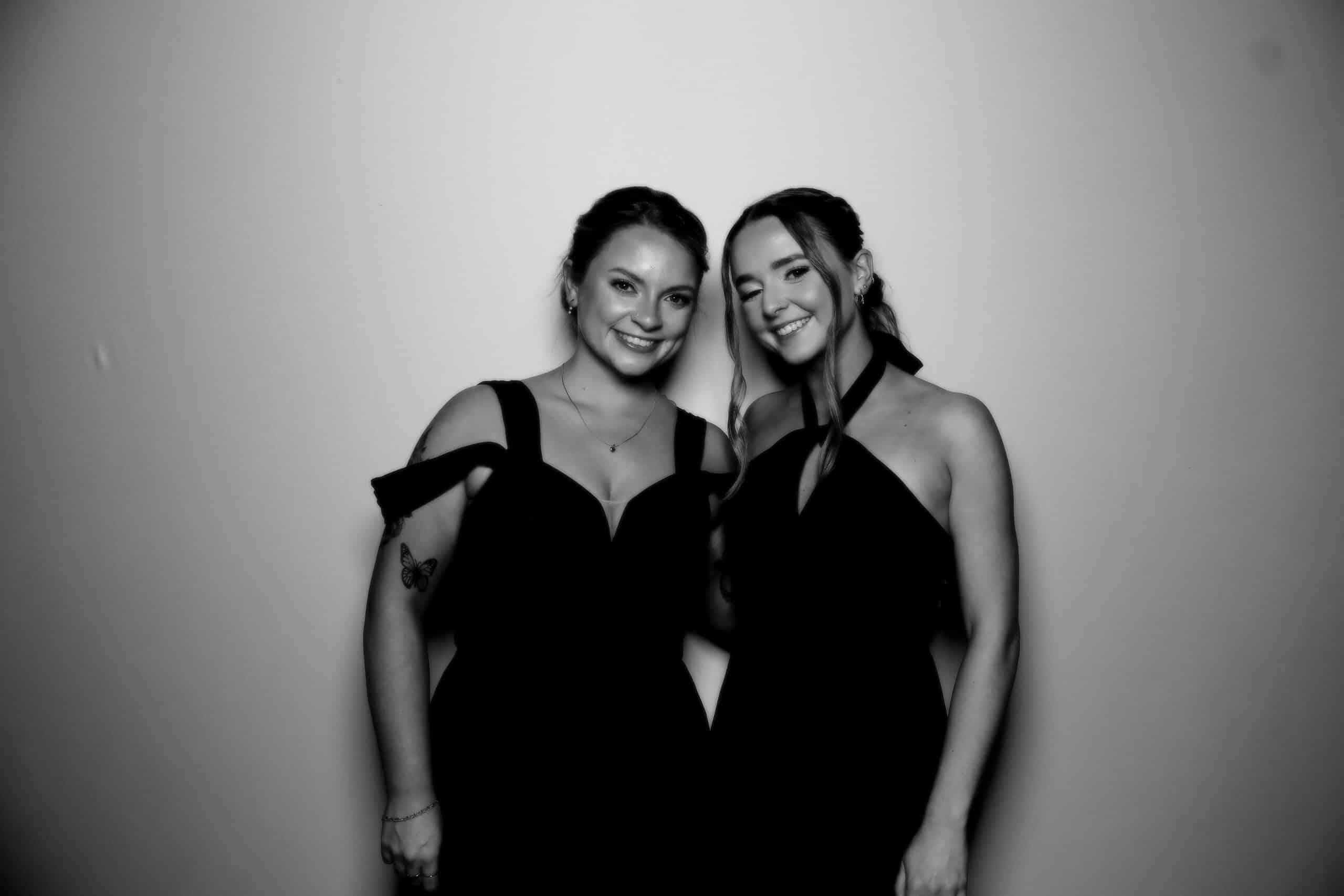Two woman posing at a wedding for a black and white photo.