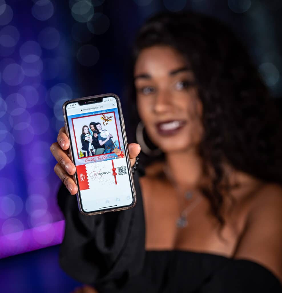 A girl holding a phone showing a digital example of a photo taken on a photo booth with a custom frame and design